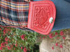 Red Mini Tamara Saddle Bag with Embossed Leather Held by Person Outdoors Wearing Blue Jeans and Tartan Shirt