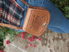 Tan Mini Tamara Saddle Bag with Embossed Leather Held by Person Outdoors Wearing Blue Jeans and Tartan Shirt