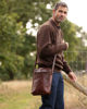 The Martil Large Messenger Bag in Dark Brown Worn by Man on Lifestyle Background